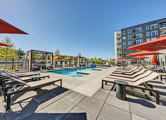 A sunny day at the pool with red umbrellas and benches. at The Mera, St Louis Park, MN, 55426