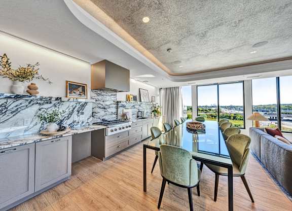 A modern kitchen with a marble countertop and a dining table set for six. at The Mera, St Louis Park, MN, 55426