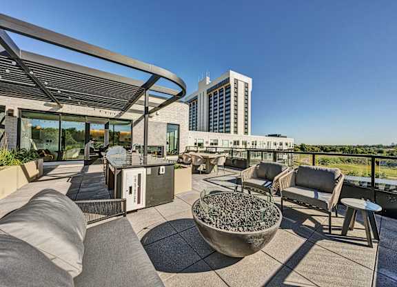 A patio with a table, chairs, and a bowl of rocks. at The Mera, St Louis Park, MN, 55426