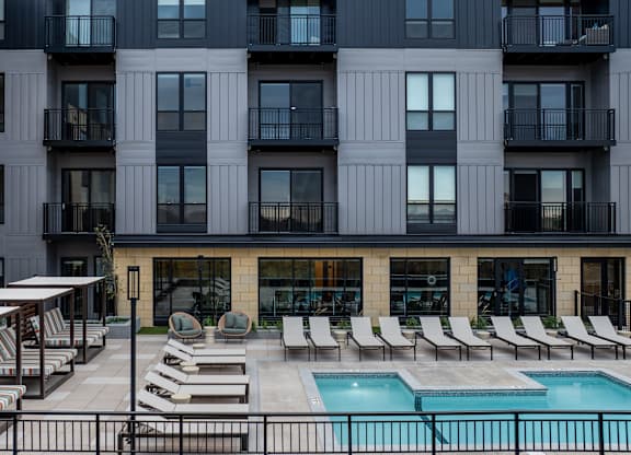 A large building with a pool and lounge chairs in front.at Lilia, Lilydale, MN, 55118