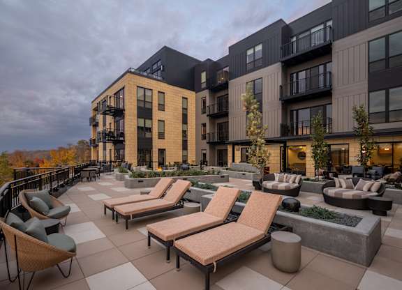 A modern outdoor seating area with lounge chairs and planters is surrounded by contemporary buildings. at Lilia, Minnesota