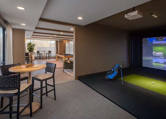 A room with a golf simulator and a dining table. at Lilia, Minnesota