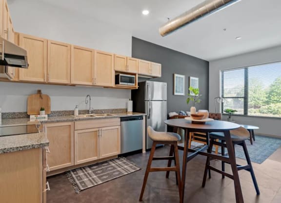 a kitchen with wooden cabinets and a table with chairs at Zelia on Seven, St Louis Park