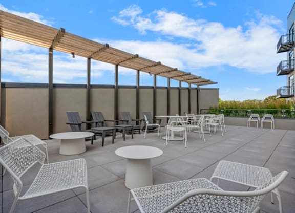 a patio with chairs and tables on the roof of a building at Zelia on Seven, St Louis Park, MN, 55416