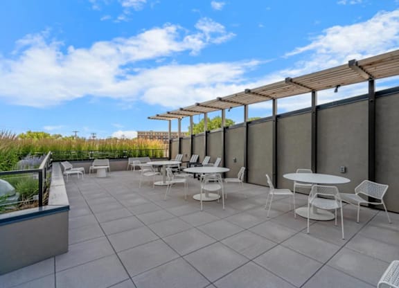 a patio with tables and chairs on the roof of a building at Zelia on Seven, St Louis Park, 55416