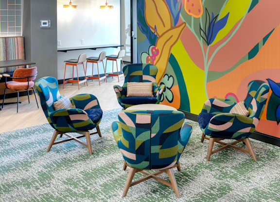 A room with chairs and a mural of flowers and a hanging light fixture.