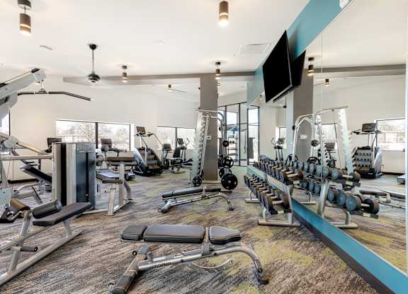A gym with a variety of equipment including weights and machines.