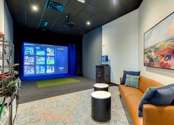 Golf and game simulator with a brown leather couch