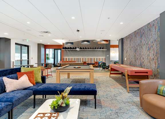 A room with billiards, shuffleboard and seating areas