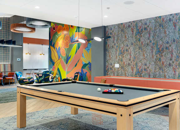 A pool table in a room with a colorful mural on the wall.