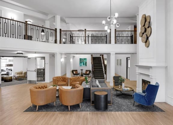 a shared common area with chairs, fireplace, stairway, and balcony.