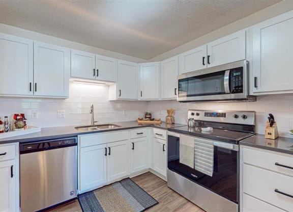 a kitchen with white cabinets and a stove and a microwave