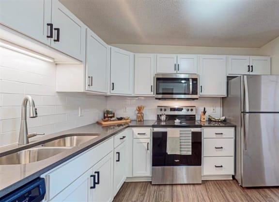 a kitchen with white cabinets, stainless steel stove and stainless steel microwave