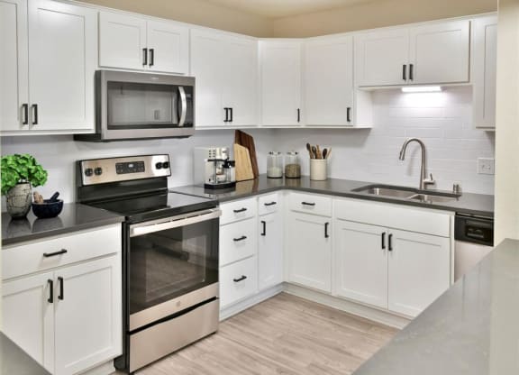 a white kitchen with stainless steel appliances and white cabinets