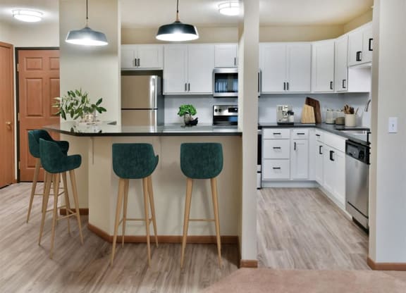 a kitchen with white cabinets and a counter with three stools