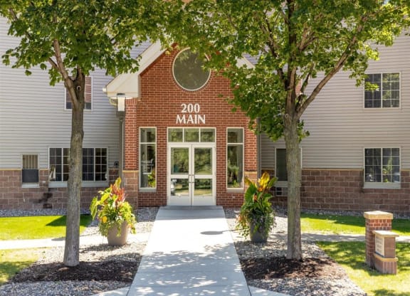 the front entrance of a building with trees and a sidewalk
