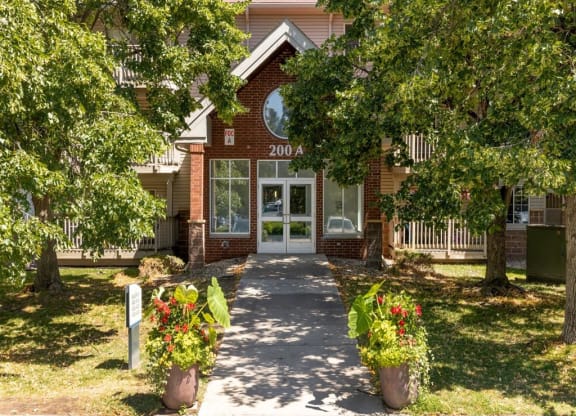 the front entrance of a red brick house with trees and a sidewalk