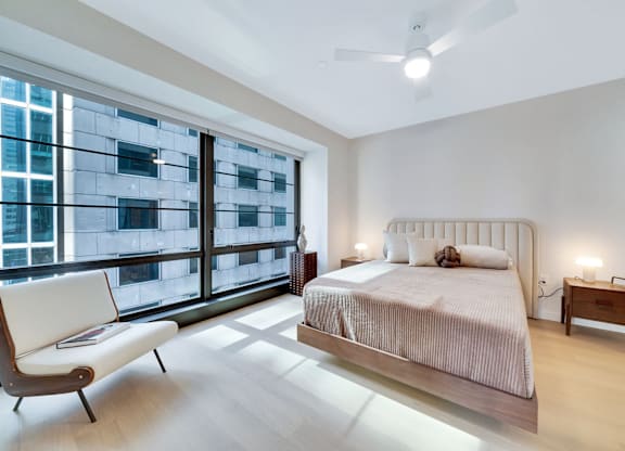 A bedroom with a large bed, a chair, and a window overlooking a cityscape. at 17 Market West, Philadelphia, PA