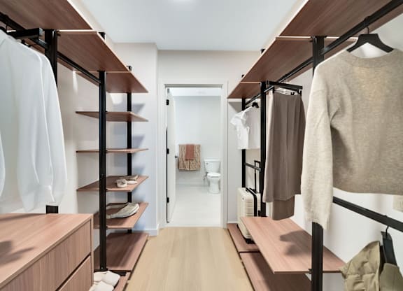 A walk-in closet with clothes hanging and shelves.