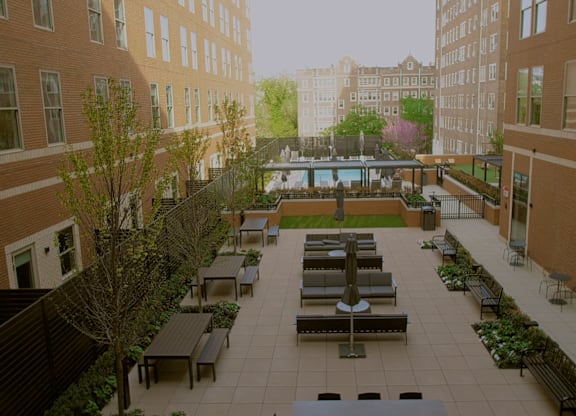 A courtyard with benches and a table surrounded by buildings.