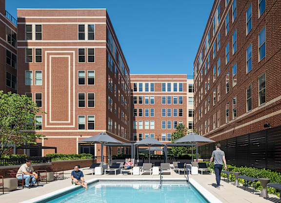 A man is walking in a courtyard with a pool.