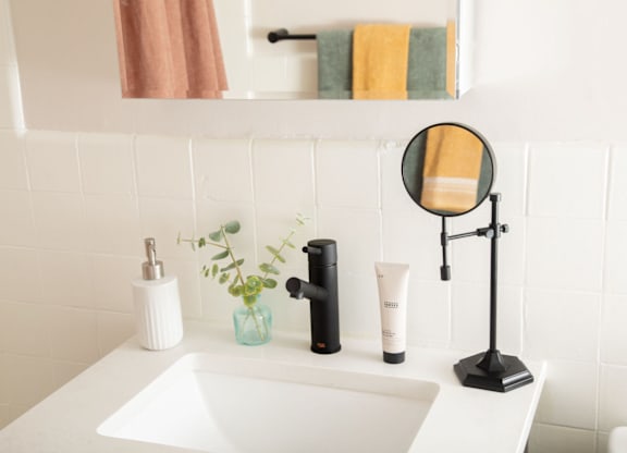 A white sink with a black faucet and a mirror above it.