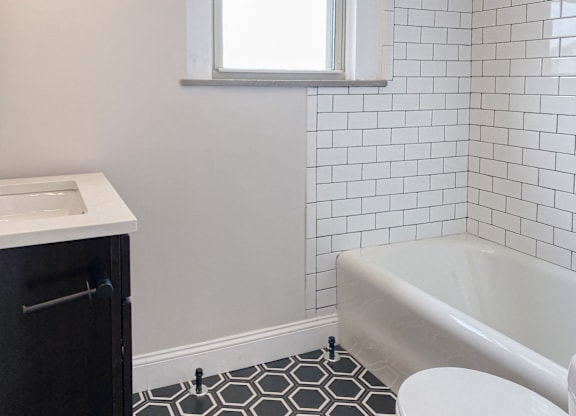 A white bathroom with a black and white hexagonal tile floor.