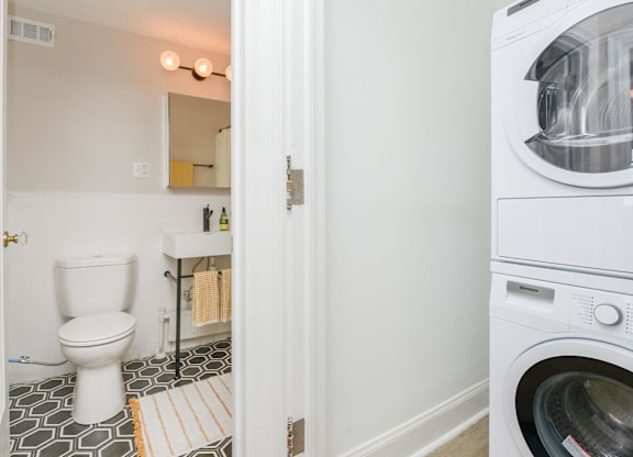 A white toilet in a small bathroom with a washing machine in the background.