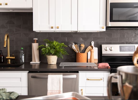 A kitchen with white cabinets and black countertops.