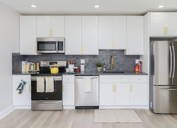 A modern kitchen with white cabinets and a stainless steel refrigerator.
