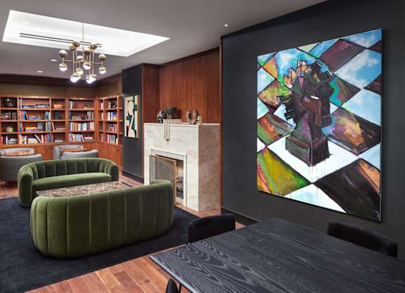 A living room with a fireplace, bookshelves, and a large painting on the wall.