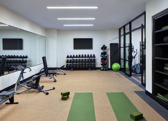 A gym with exercise equipment and a green mat on the floor.