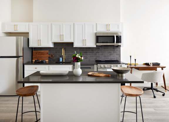 a kitchen with white cabinets and a black counter top