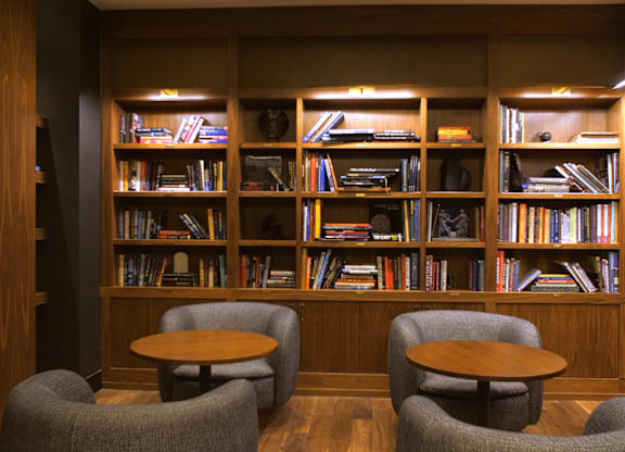A room with a bookshelf and two grey chairs.