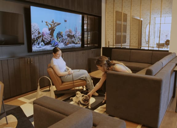 Two people sitting in a room with a large screen on the wall.