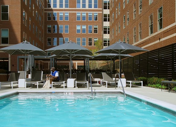 A swimming pool surrounded by chairs and umbrellas in a courtyard.