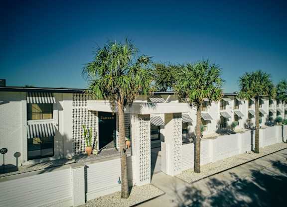 A row of white buildings with palm trees in front at The PARKER on E Mulberry Apartments, San Antonio, TX