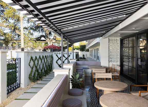 A patio with a black and white striped awning and a table with chairs at The PARKER on E Mulberry Apartments, San Antonio