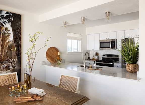 A modern kitchen with a wooden table and chairs at The PARKER on E Mulberry Apartments, Texas
