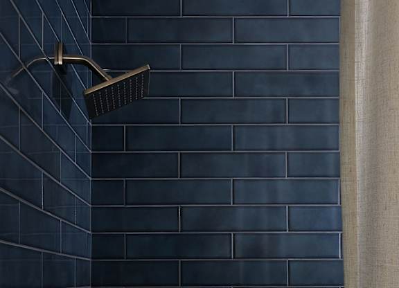 A black shower head mounted on a wall at The PARKER on E Mulberry Apartments, Texas