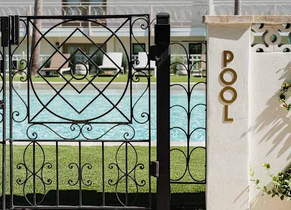 A pool with a black fence and a white pillar with the word POOL on it at The PARKER on E Mulberry Apartments, San Antonio, TX