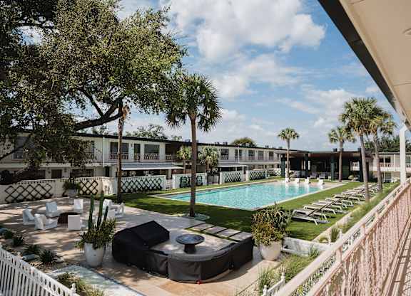 A pool area with lounge chairs and a white fence at The PARKER on E Mulberry Apartments, San Antonio, TX, 78209