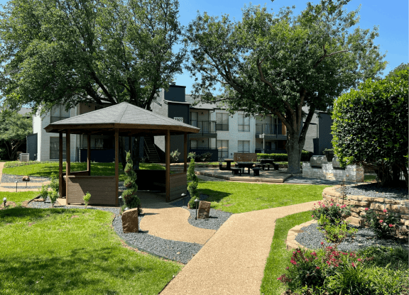 a park with a gazebo and trees in front of an apartment building at District 2308, Texas 