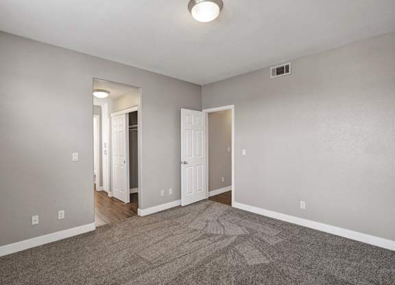 A room with a carpeted floor and a doorway leading to another room.