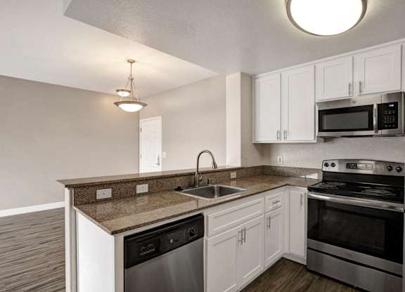 A kitchen with white cabinets and a granite countertop.