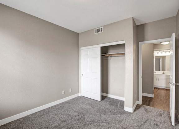 A room with a white door and a grey carpet.