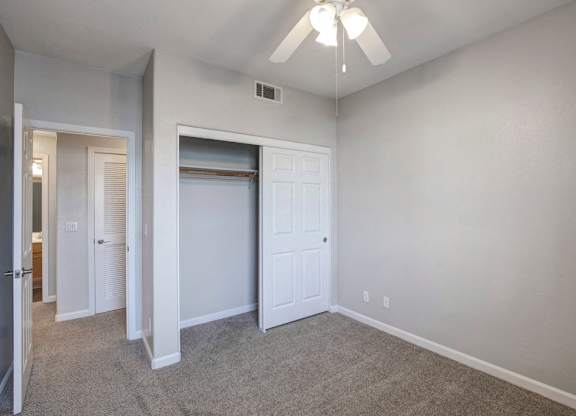A room with a white door and a ceiling fan.