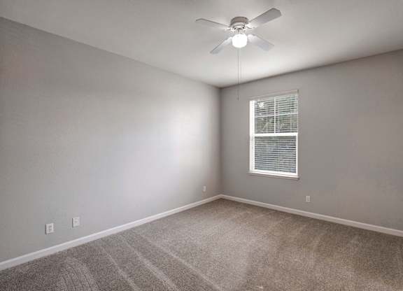 A room with a ceiling fan and a window with blinds.