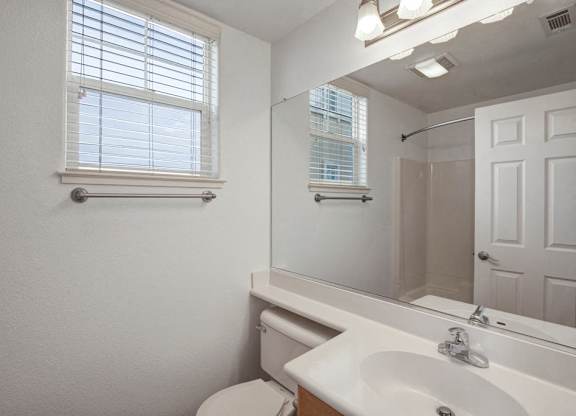 A white bathroom with a toilet, sink, and mirror.