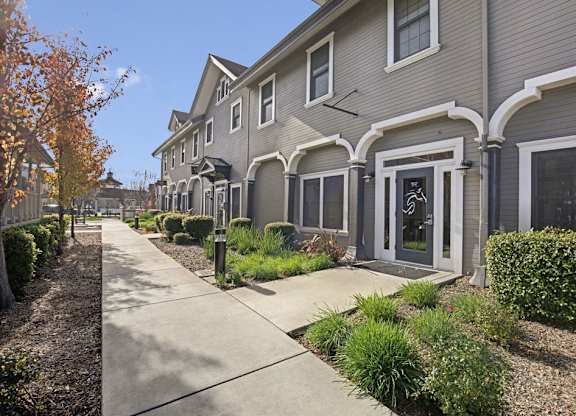 A row of houses with a sidewalk in front.